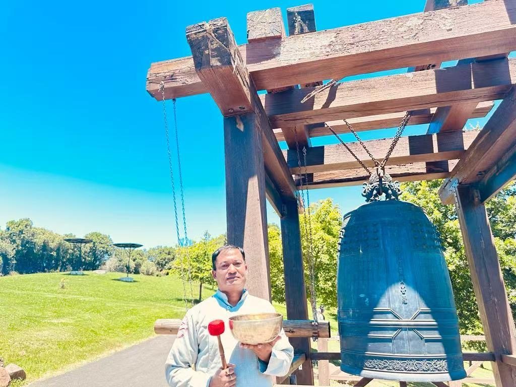 Saroj Shakya with singing bowl at outdoor bell site in Australia